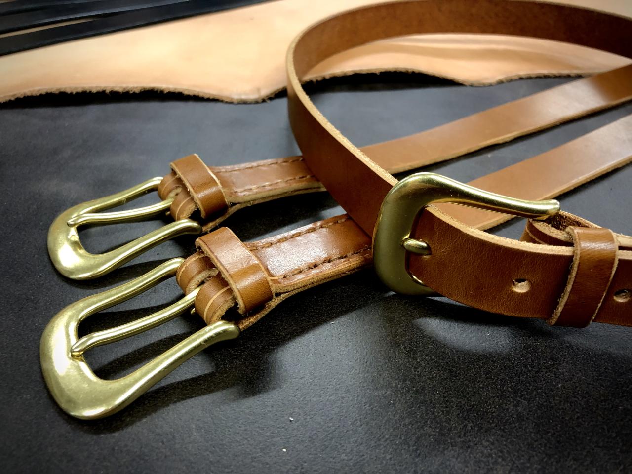 Kolme konjakin ruskeaa nahkavyötä messinkisoljilla.